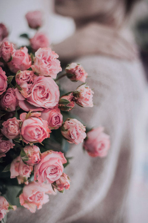 Bouquet of spray pink roses held by a person with a blurred background