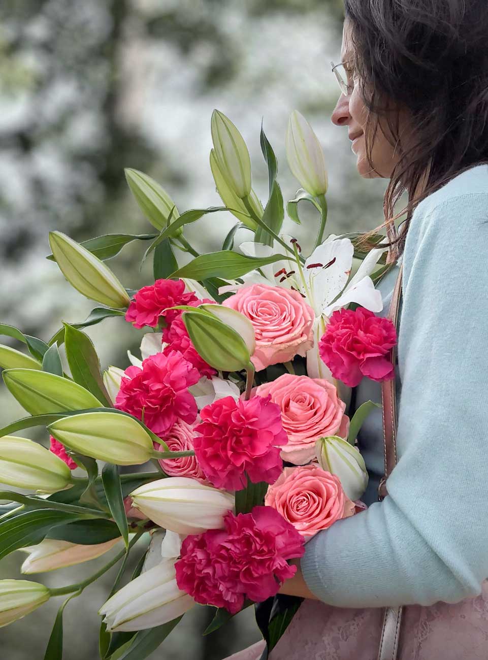 Woman holding a bouquet of lilies paired with pink and hot pink flowers