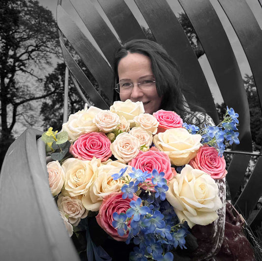Woman holding a bouquet of white, pink and blue flowers 