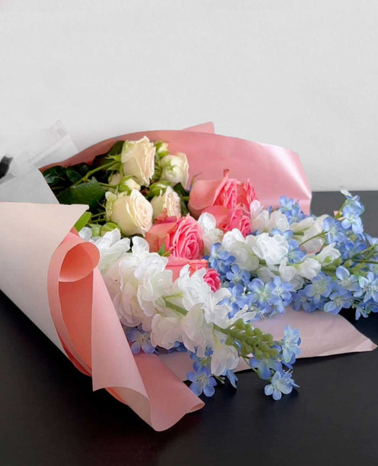 Bouquet of flowers with pink, white, blue and cream flowers on a  dark surface