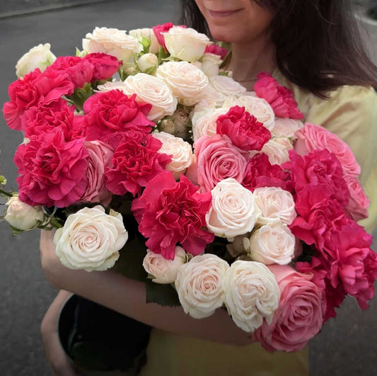 Bouquet of pink, hot pink and white flowers held by a person