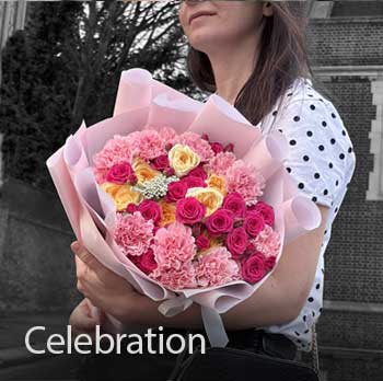 Person holding a bouquet of pink, hot pink yellow flowers outdoors.