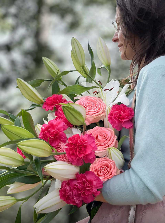 Woman holding a bouquet of lilies paired with pink and hot pink flowers